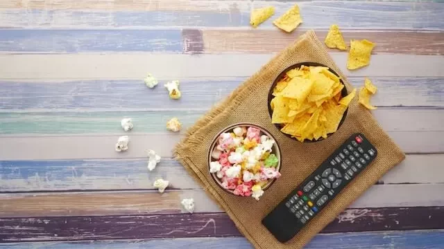 different types of corn chips and popcron in two saperate bowls lying on a wodden tray.